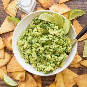 overhead shot of bowl of guac with tortilla chips surrounding