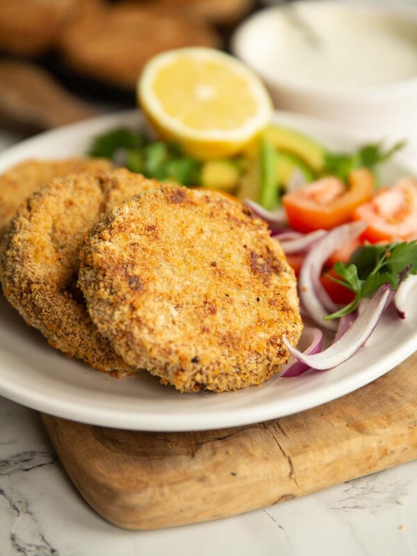 tuna patties plated with salad on white plate with dip and more patties blurred in background