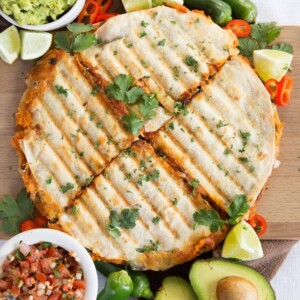 overhead shot of quesadillas sliced into 4 garnished with chilli, jalapeno and coriander