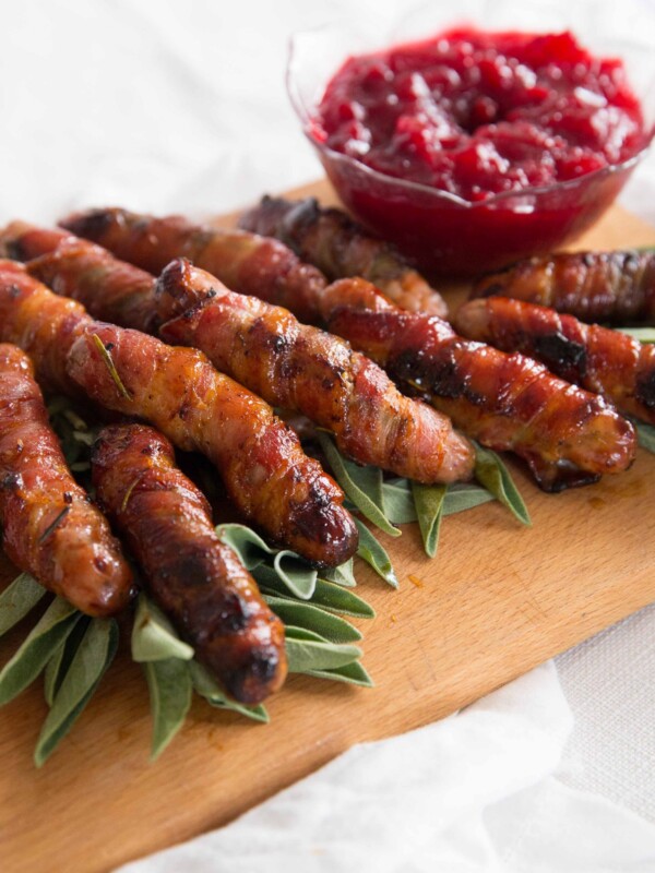 pigs in blankets stacked up on chopping board on bed of sage