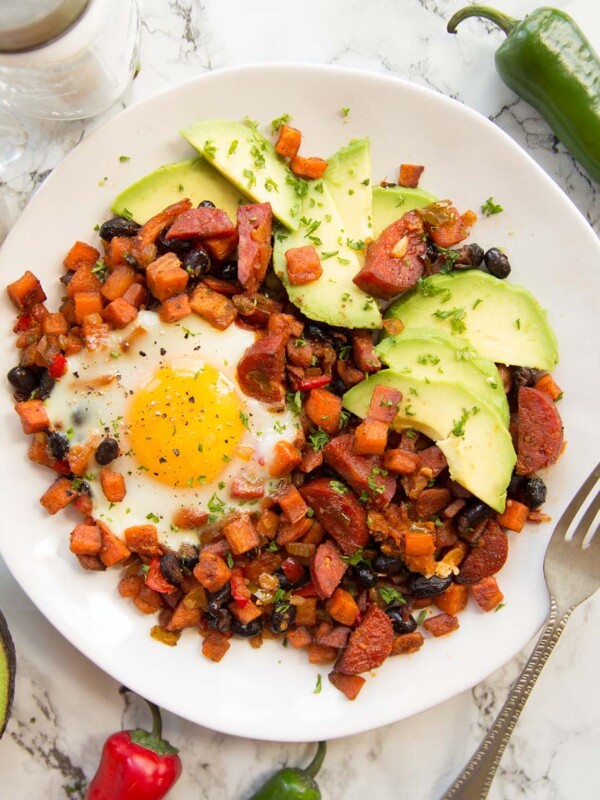 overhead shot of Sweet Potato Breakfast Hash on white plate served with avocado slices