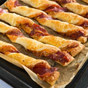 row of cheese and prosciutto twists on black tray fresh out the oven