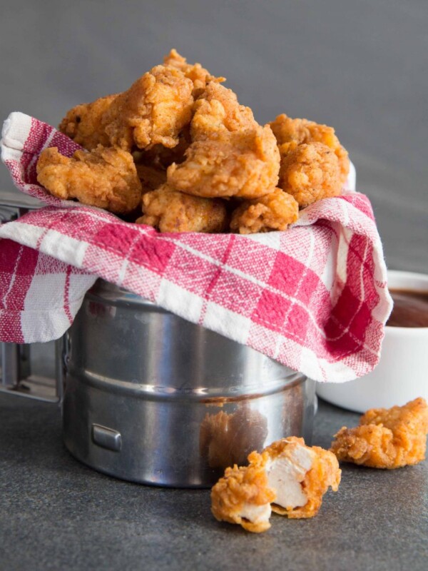 Popcorn Chicken in metal tub wrapped in tartan cloth with BBQ sauce in the background