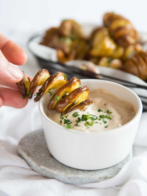 hand dipping tornado fry into small white pot of dip