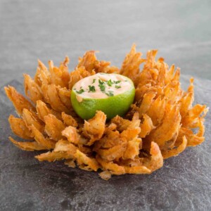 blooming onion served with lime dipping bowl in the centre on slate