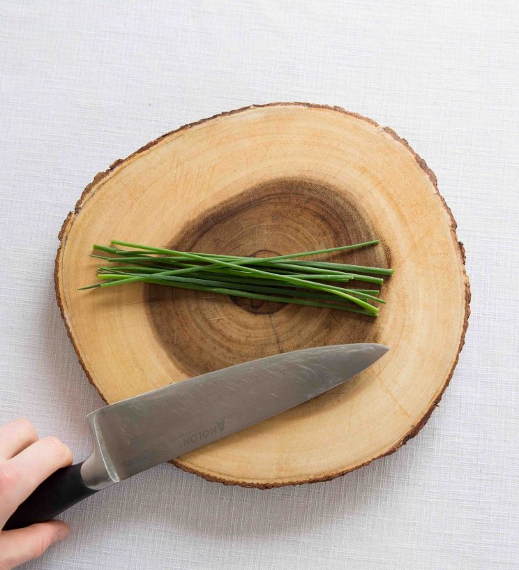 wooden board with fresh chives and sharp knife