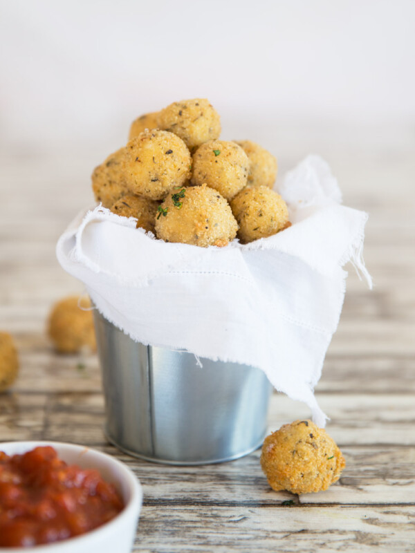 cheese balls served in a tin bucket with marinara dip blurred in the front