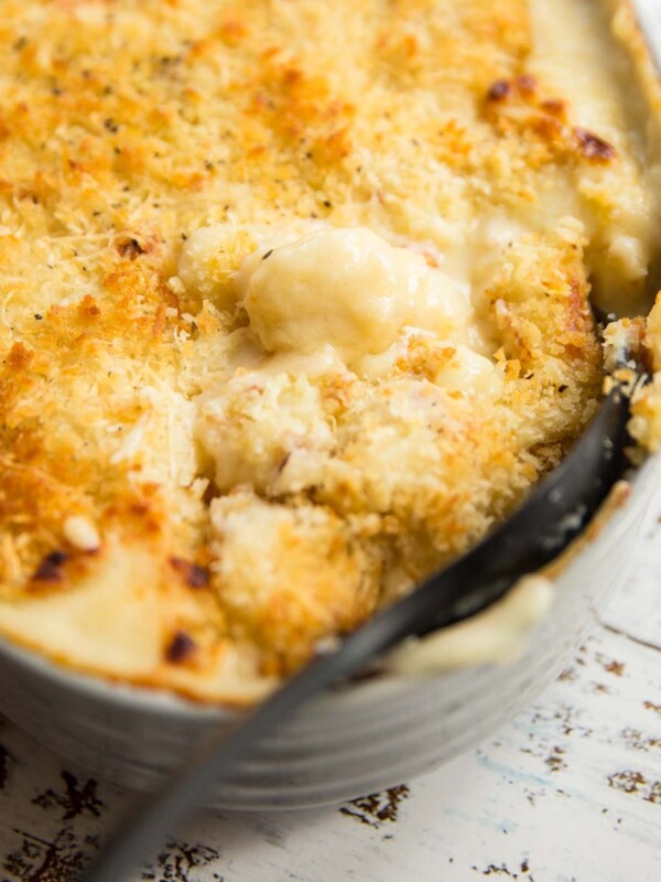 Scooping into baked gnocchi mac and cheese with large black spoon