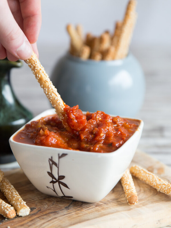 dunking a breadstick in dip with more breadsticks blurred in the background