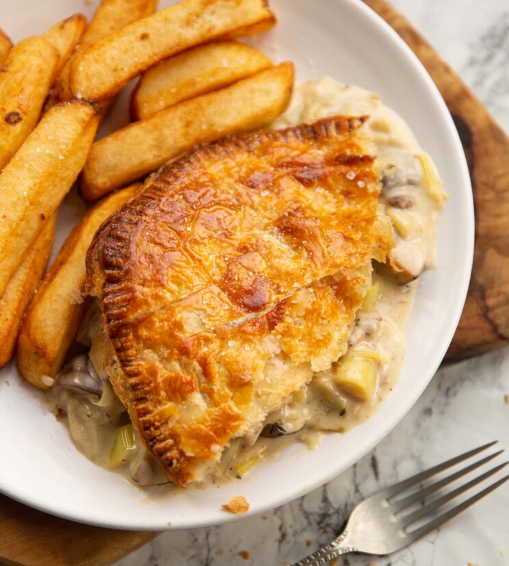 chicken leek mushroom pie served on small white plate with chips