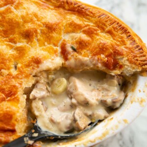 close up shot of black serving spoon digging into chicken leek mushrooms pie