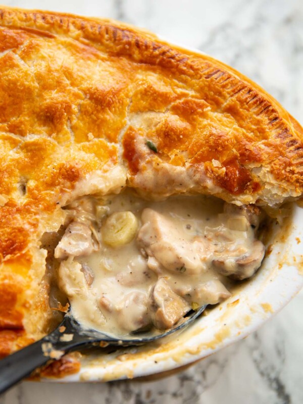 close up shot of black serving spoon digging into chicken leek mushrooms pie