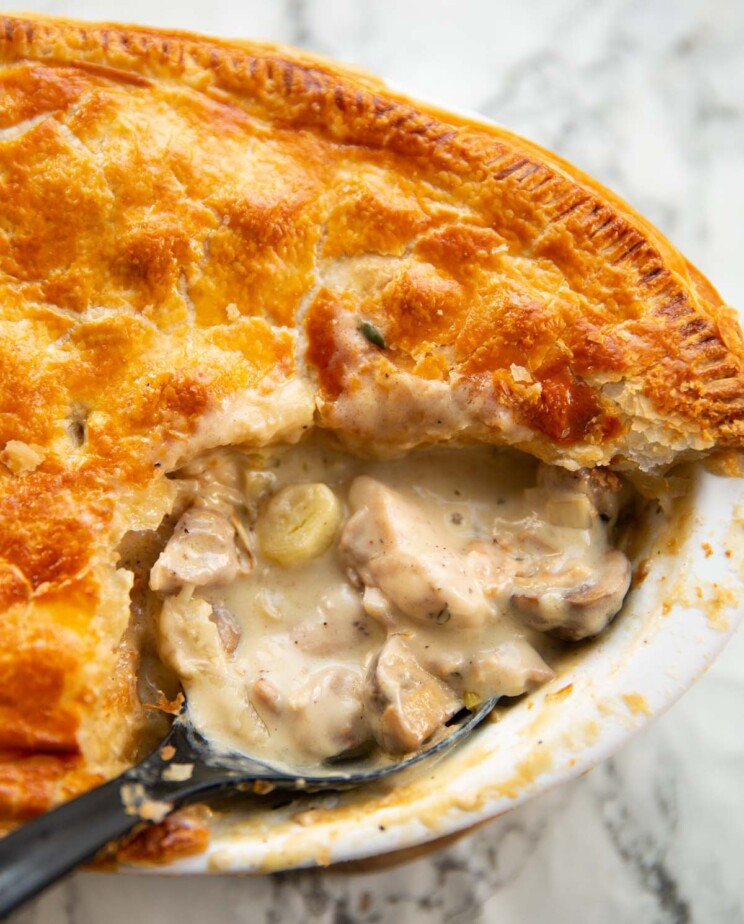 close up shot of black serving spoon digging into chicken leek mushrooms pie