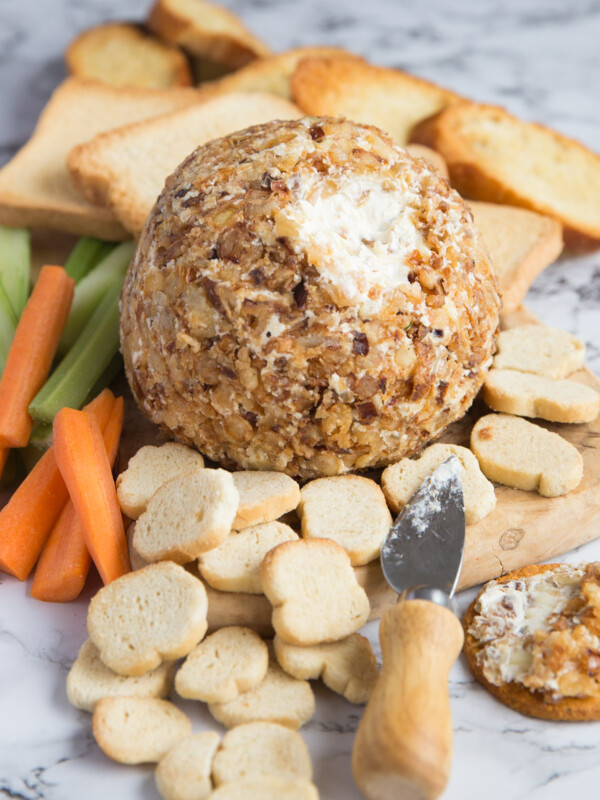 cream cheese ball coated in crispy fried onions on chopping board with biscuits and bread