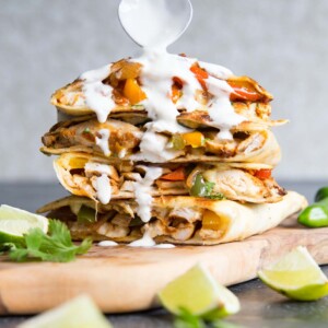 quesadillas stacked on each other with heart shaped spoon pouring over sour cream