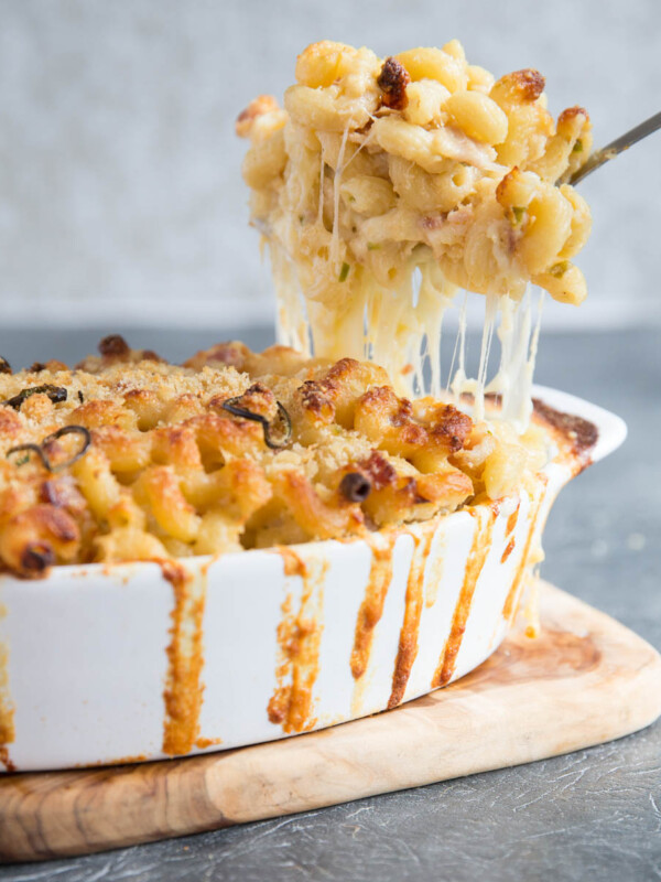 scooping spicy mac and cheese out of baking dish with cheese pull