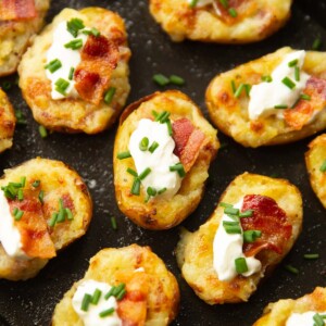 close up shot of mini loaded potatoes on black oven tray