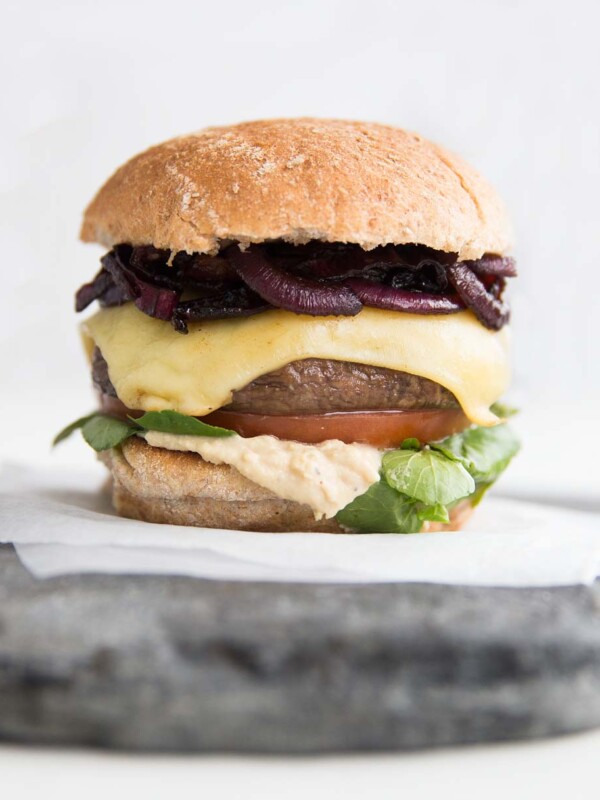 close up shot of Portobello Mushroom Burger with caramelised onions, cheese, hummus, tomato and watercress