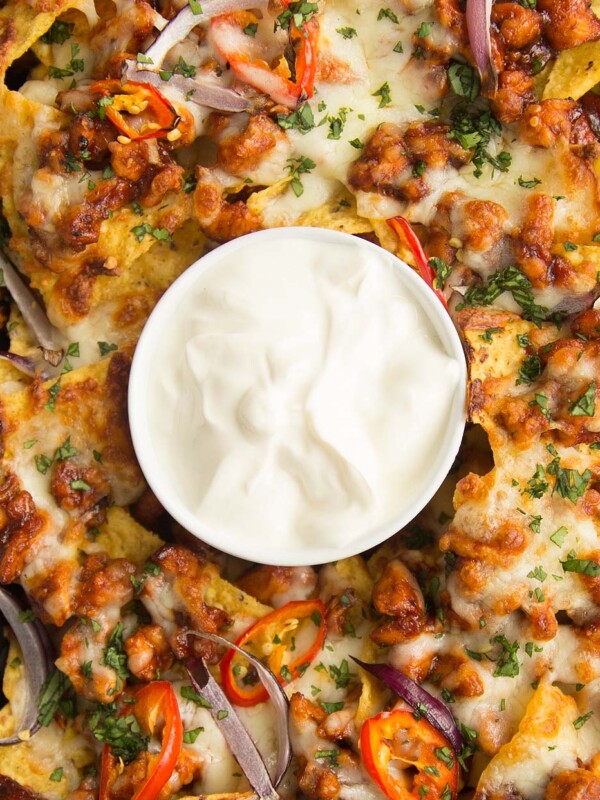 overhead shot of BBQ Chicken Nachos on a tray with sour cream in the middle