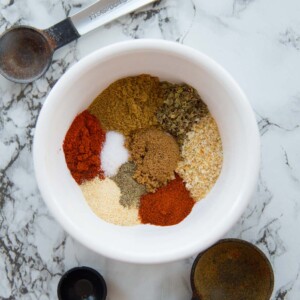 Small bowl with taco seasoning surrounded by measuring spoons