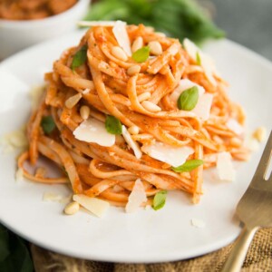 Sun Dried Tomato Pesto Pasta on a white plate with a gold fork and basil in the background