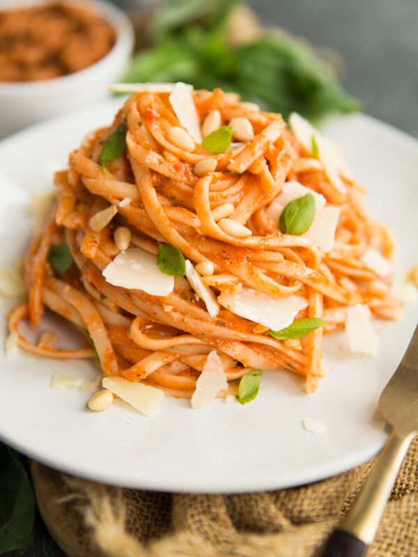 Sun Dried Tomato Pesto Pasta on a white plate with a gold fork and basil in the background