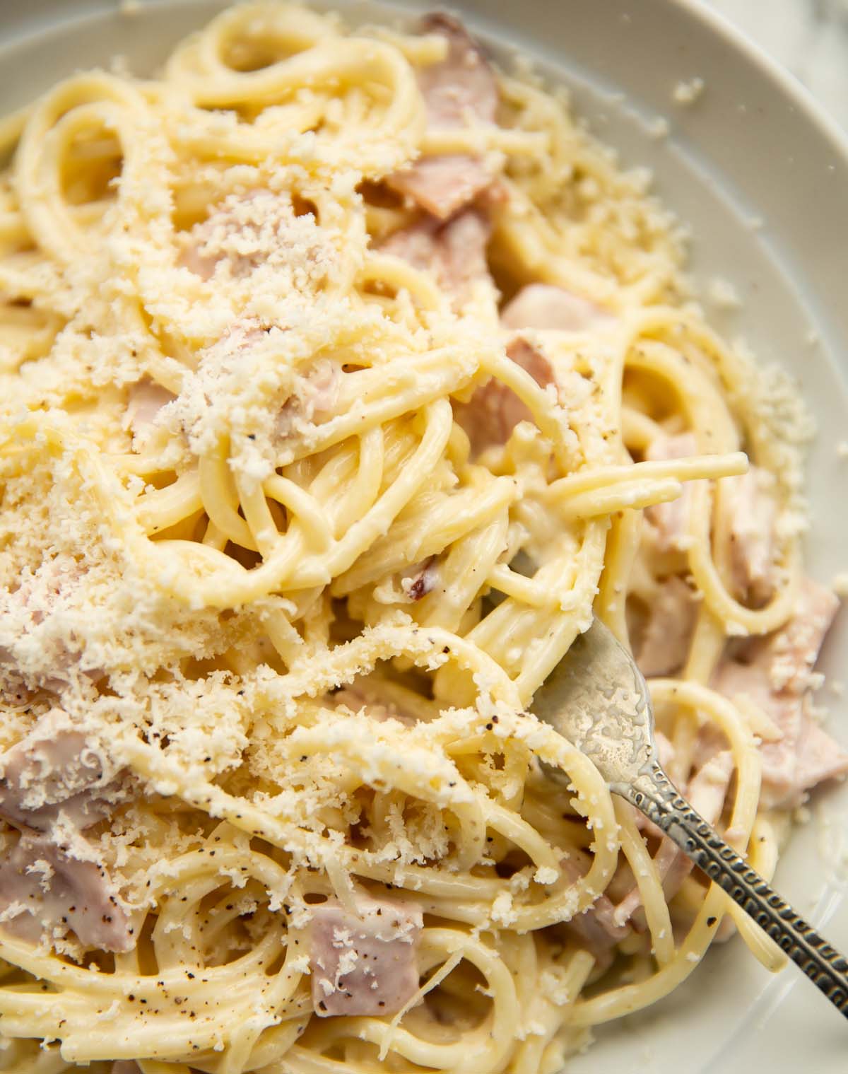 close up overhead shot of cream cheese pasta with silver fork digging in