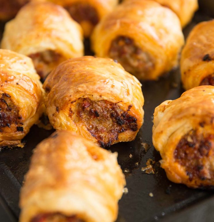 closeup of chorizo sausage rolls fresh out the oven on black baking tray