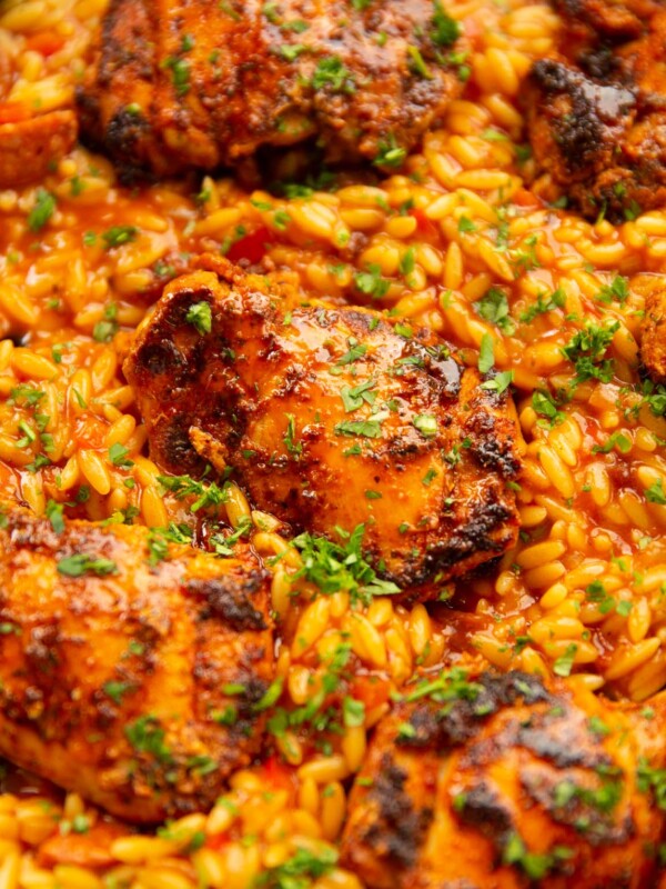 close up shot of spanish chicken orzo in pan garnished with parsley