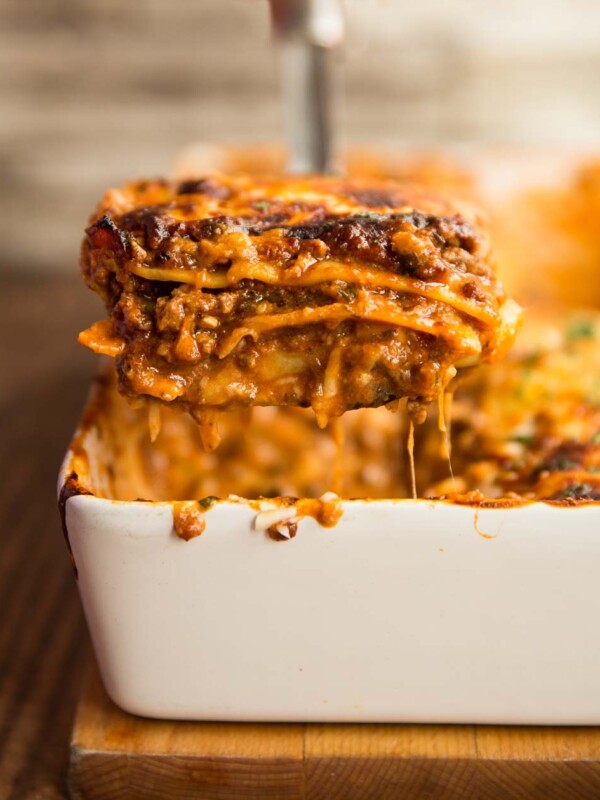 one serving of lasagne being lifted from the baking cheese with cheese hanging off