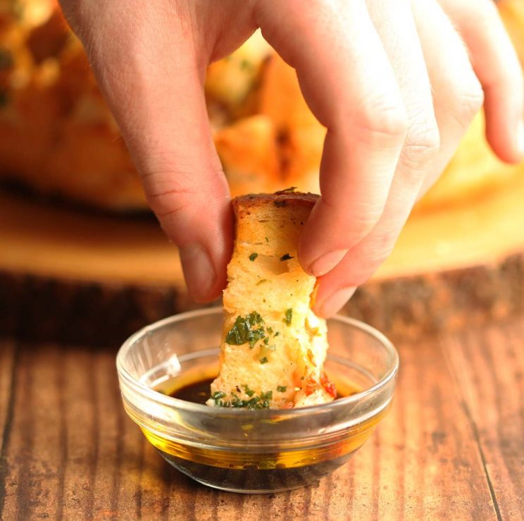 dipping pull apart bread into balsamic and olive oil dip