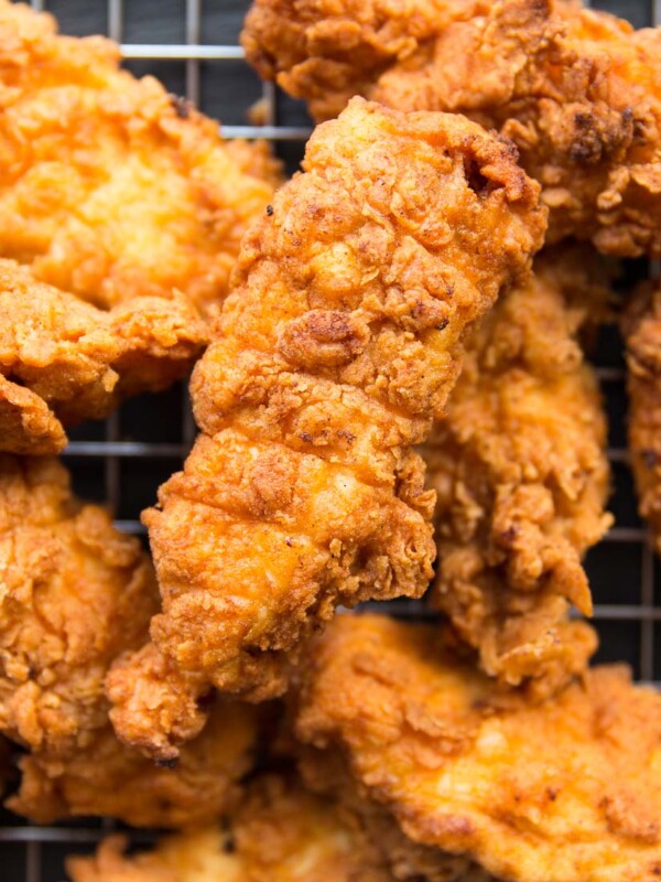 overhead shot of chicken tenders resting on a wire rack, focus on one tender surrounded by the rest.