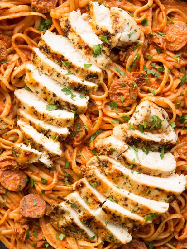 overhead shot of chorizo pasta and sliced grilled chicken on top in pan