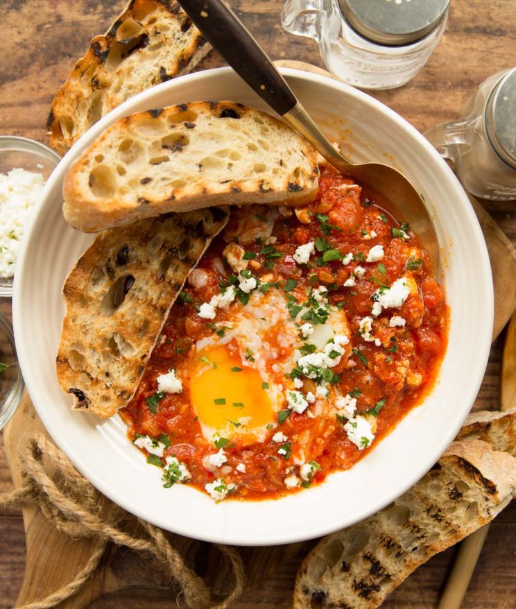 shakshuka served in a white bowl with toasted ciabatta