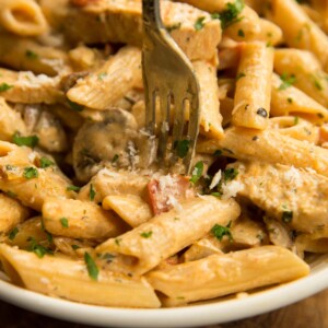 cajun chicken pasta served in white bowl with fork digging in