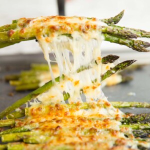 pulling cheesy asparagus off tray with spatula