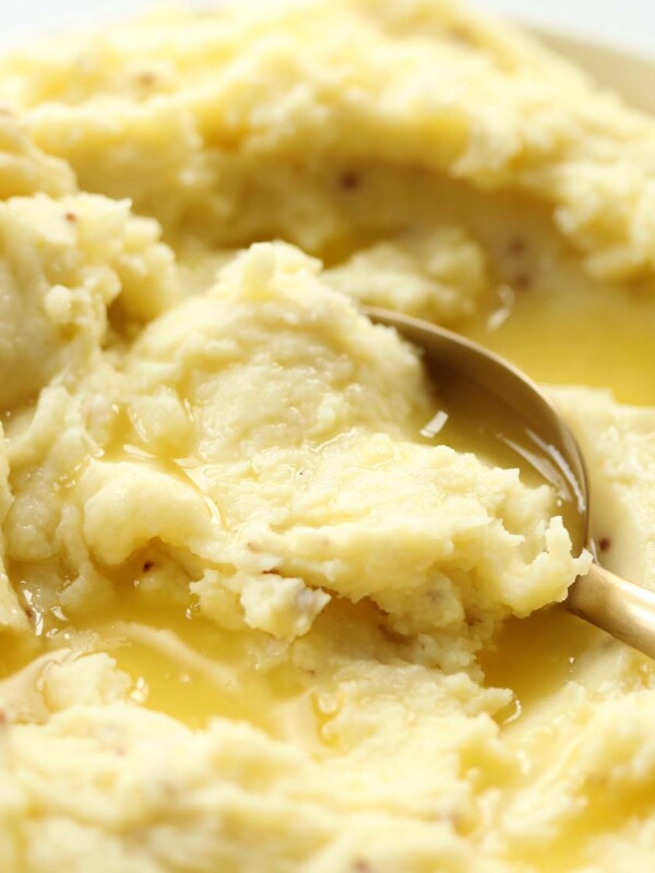 spoon digging into mustard mash with melted butter on top