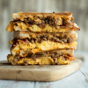 3 breakfast grilled cheese stacked on each other on wooden board