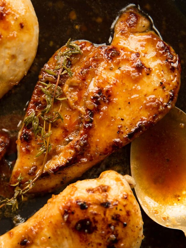 overhead shot of chicken in pan with spoon and sauce