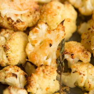 closeup shot of parmesan roasted cauliflower on baking tray with thyme