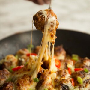 pull meatball out of skillet with fork and cheese dripping down