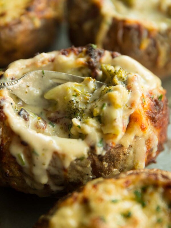 closeup shot of broccoli inside side baked potato with fork digging in