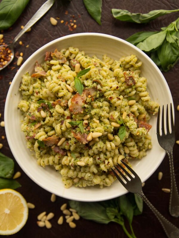 overhead shot of broccoli pesto pasta in white bowl surrounded by ingredients