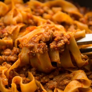 pasta tongs twirling sausage ragu in pan