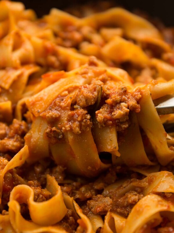 pasta tongs twirling sausage ragu in pan