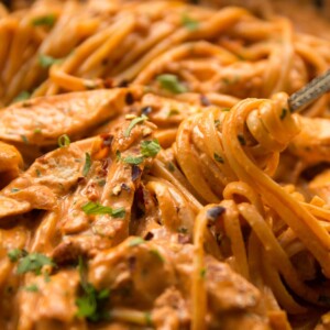 fork twizzling into chicken pasta in skillet