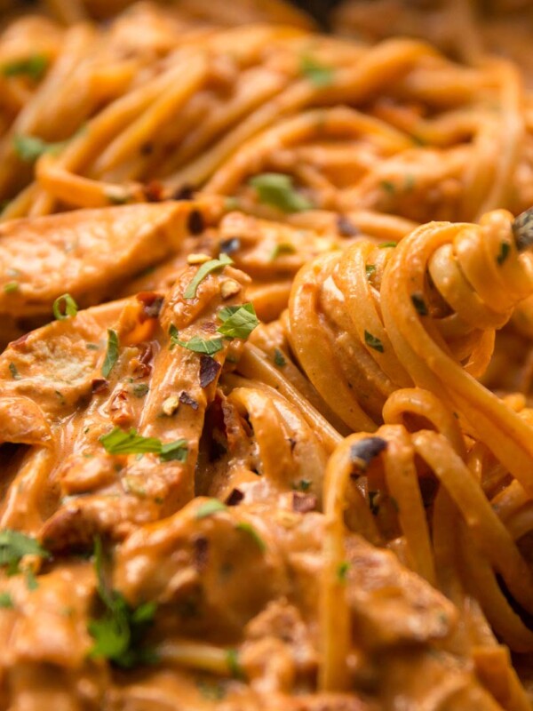 fork twizzling into chicken pasta in skillet