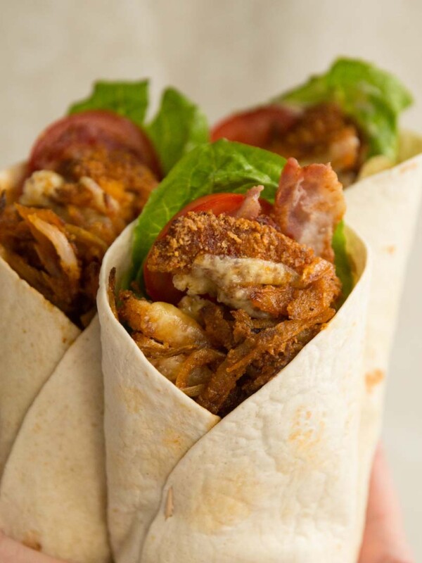 holding up crispy chicken wraps, focus on front one