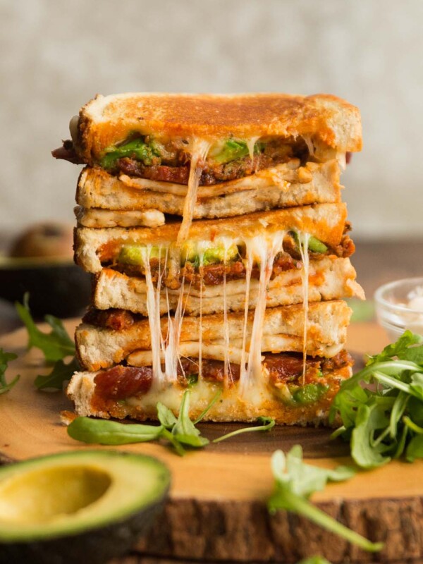 halloumi grilled cheese sandwich stacked on wooden board surrounded by rocket