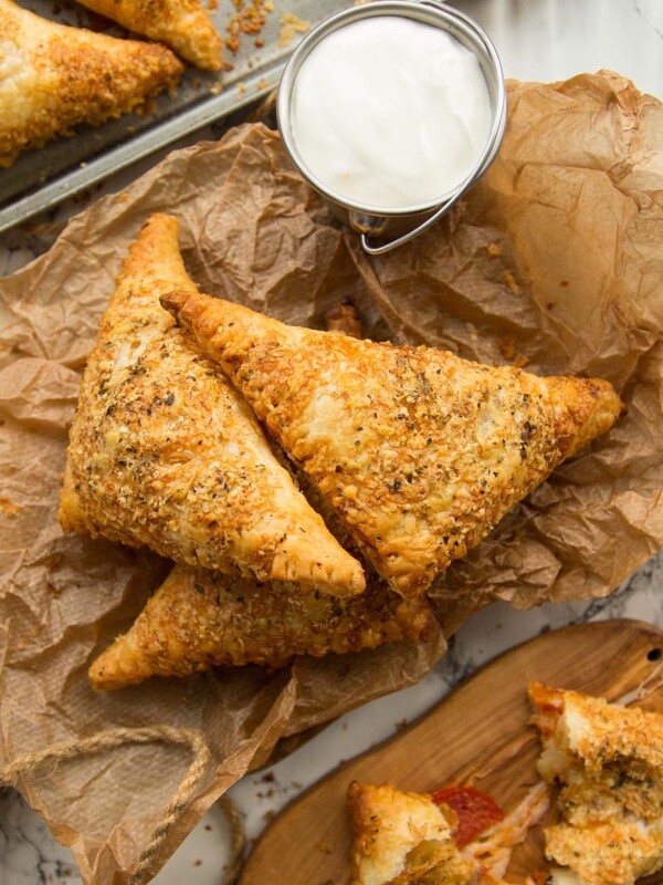 overhead shot of pizza pockets stacked on parchment paper with dip